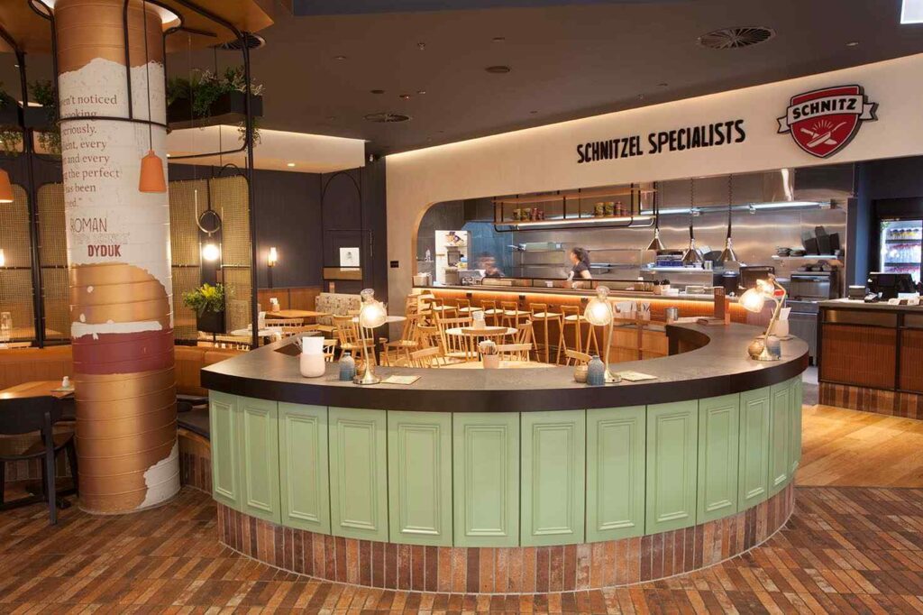 Schnitz Chadstone Front Kitchen Bench serving area by Shape Shopfitters with round green commercial joinery benchtop