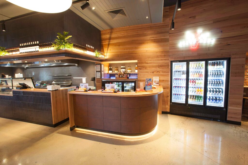 Custom commercial joinery at Grill’d Woodgrove Melbourne featuring a curved timber service counter, integrated lighting and hospitality fitout by Shape Shopfitters